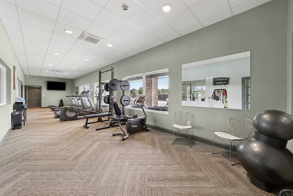 A gym with a variety of equipment including treadmills, weights, and exercise machines.