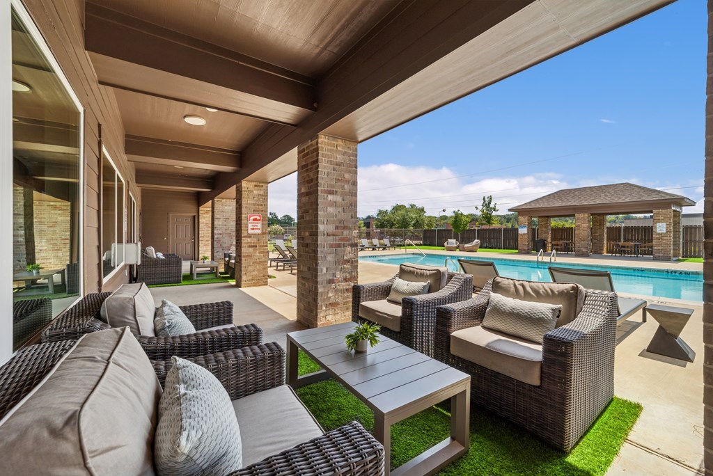 A patio with a table and chairs overlooking a pool.