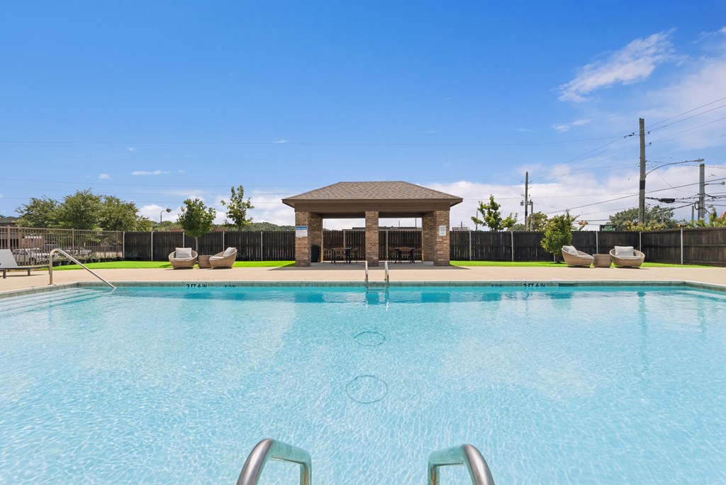 A swimming pool with a gazebo-like structure in the middle.