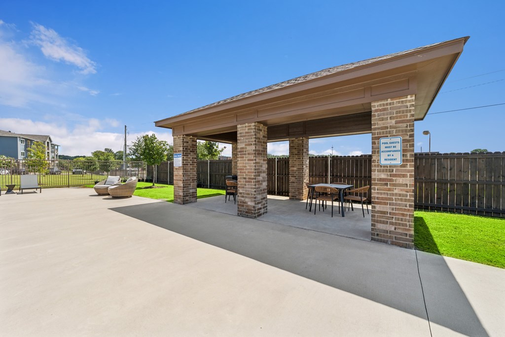 A covered outdoor seating area with a brick pillar and benches.