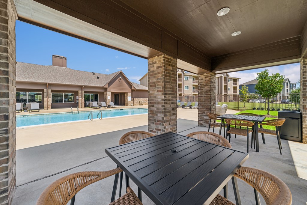 A black table is in the middle of a patio with chairs around it.