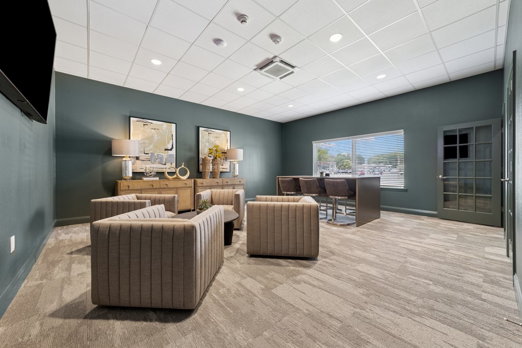 A spacious room with a grey carpet and brown furniture.