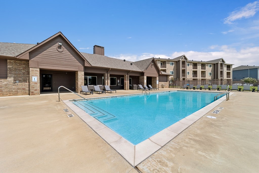 A large swimming pool in front of a building with a clear blue sky above.