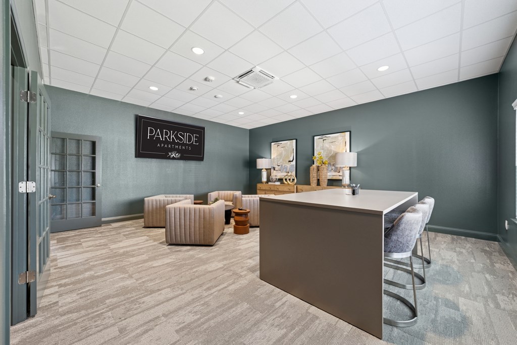 A reception area with a desk and chairs in a room with a grey wall and a door.