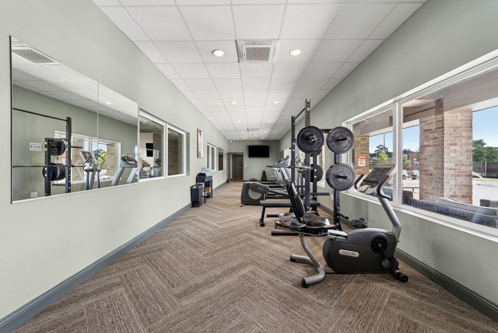 A gym with a mirror on the wall and exercise equipment.