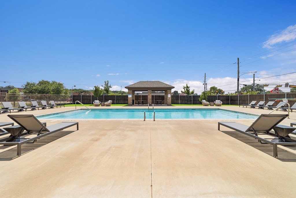 A large outdoor swimming pool with sun loungers and a pavilion.