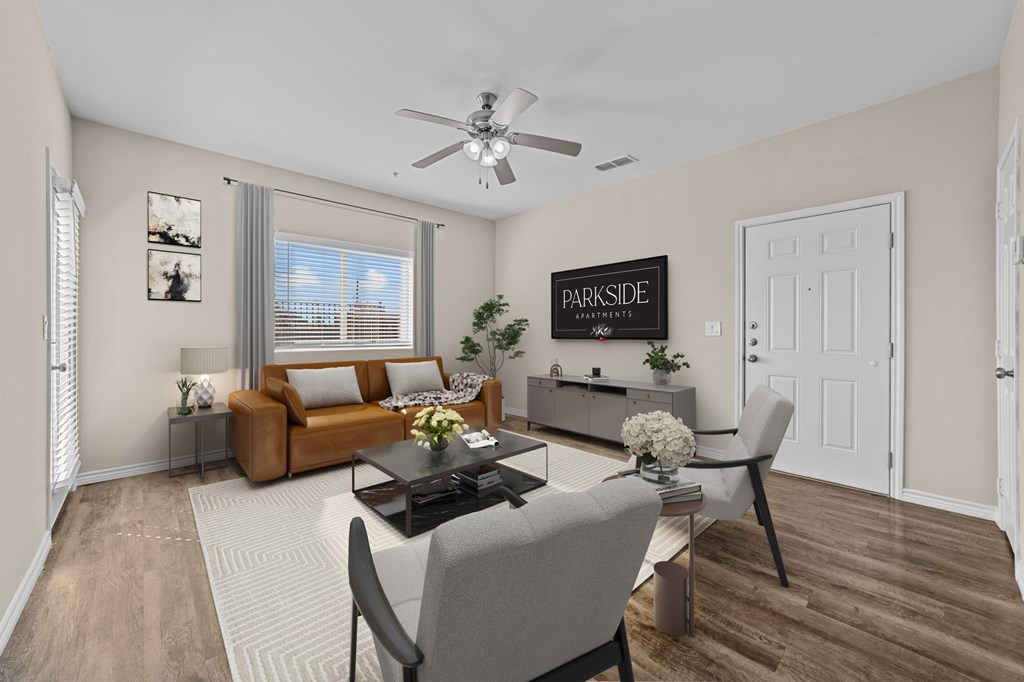 A living room with a brown couch, a coffee table, and a ceiling fan.