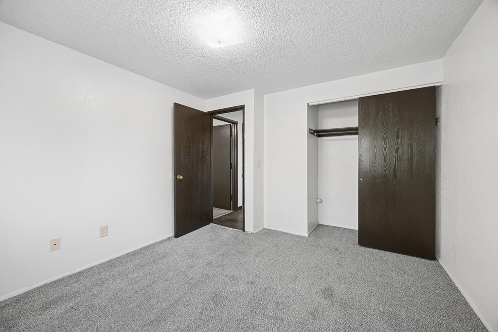 A room with a carpeted floor and two doors.