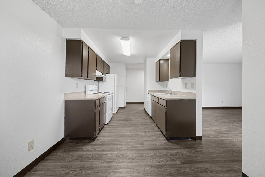 A kitchen with brown cabinets and a white wall.