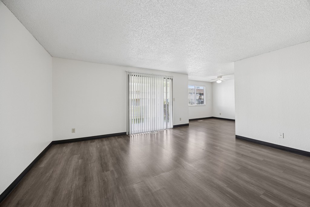 A room with a sliding glass door and wooden flooring.