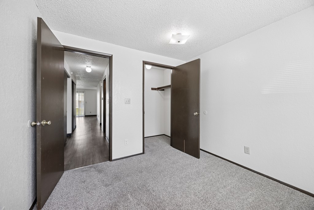A hallway with a carpeted floor and white walls.