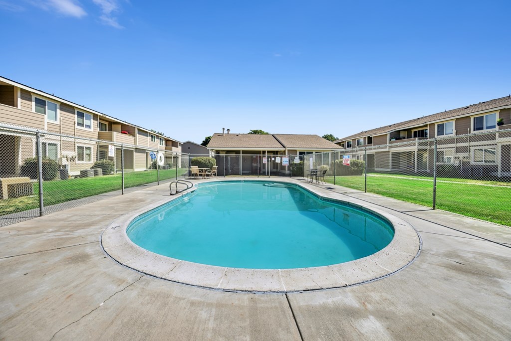 A round swimming pool in a residential area surrounded by a fence.