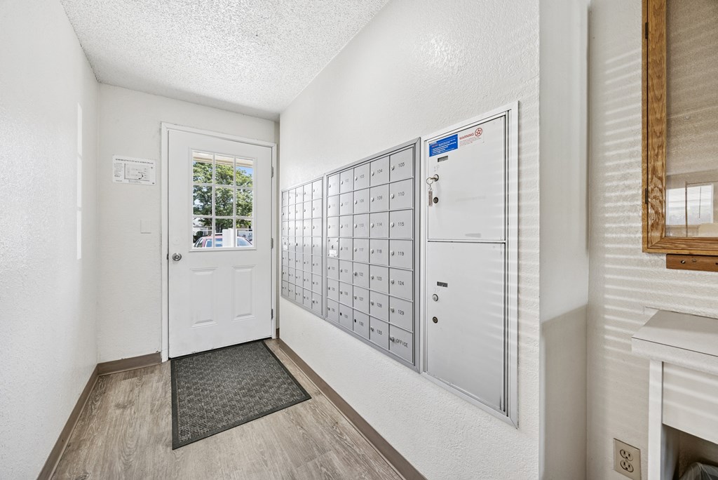 A white door is open to a hallway with a mailbox on the wall.