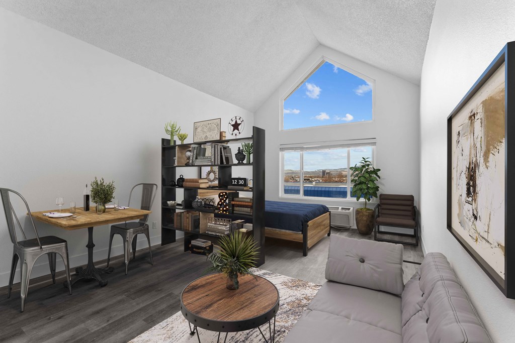 an open living room with a couch and a desk and a window
