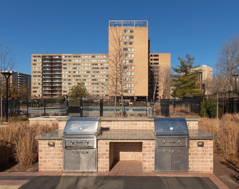 A brick structure with two ovens on top of it in front of a tall building.