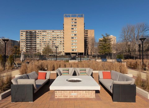 A patio with a table and chairs in front of a tall building.