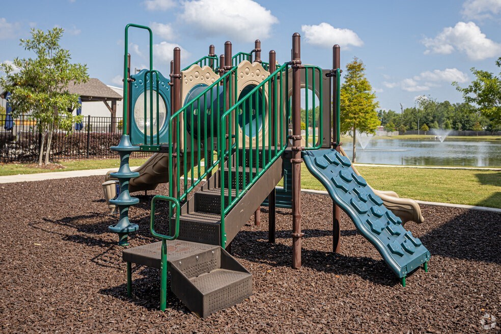 a playground with a slide and climbing equipment with a lake in the background