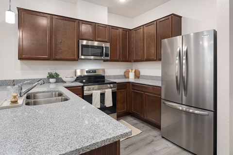 A modern kitchen with a stainless steel refrigerator and wooden cabinets.