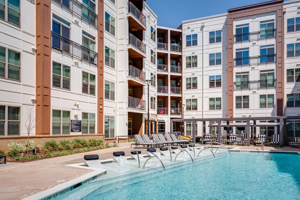 an outdoor swimming pool with chaise lounge chairs and a building in the background