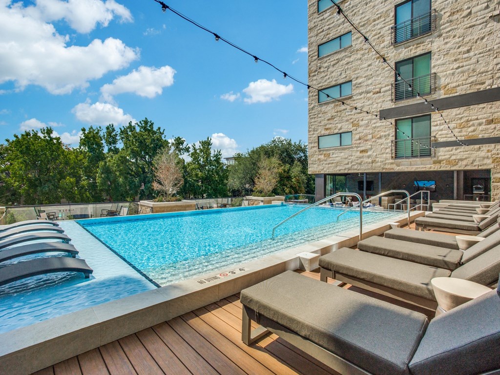 a pool with lounge chairs and a building in the background