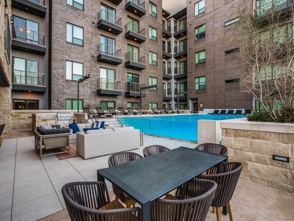 a patio with a table and chairs next to an apartment building