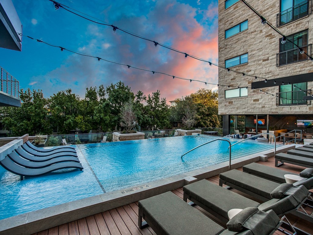 a large pool with lounge chairs and a building in the background