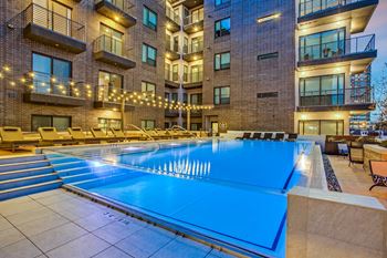 a swimming pool with a blue water feature in front of an apartment building