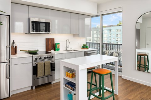 A modern kitchen with white appliances and green stools.