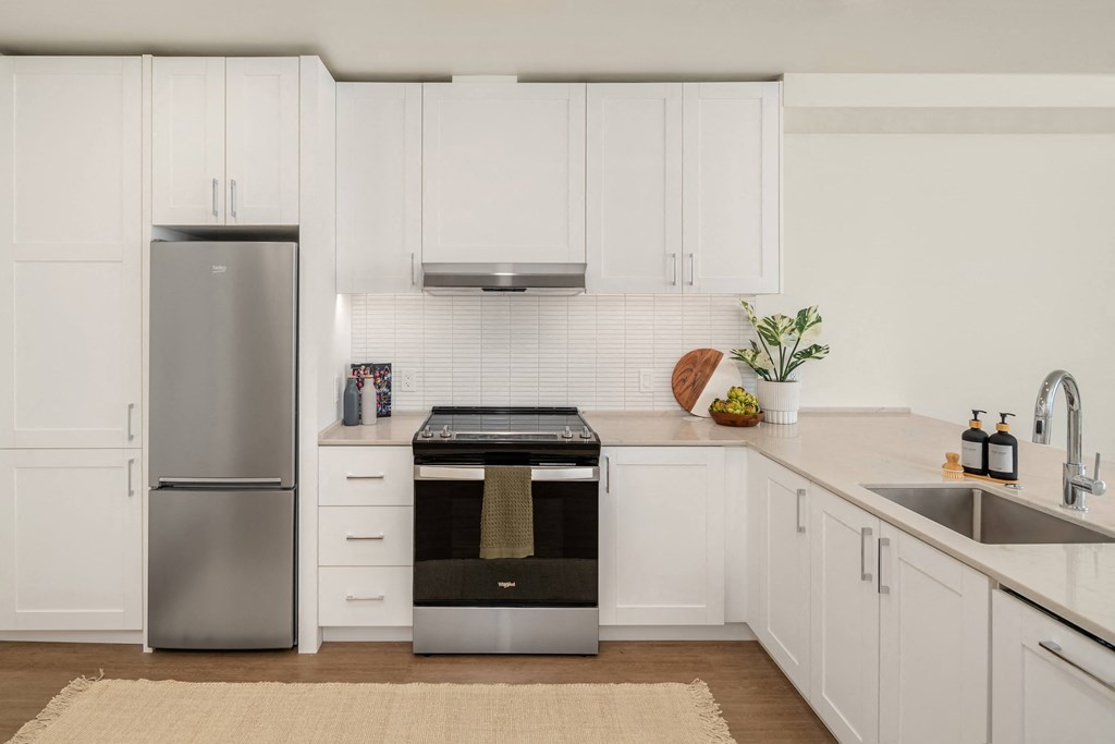 a white kitchen with stainless steel appliances and white cabinets