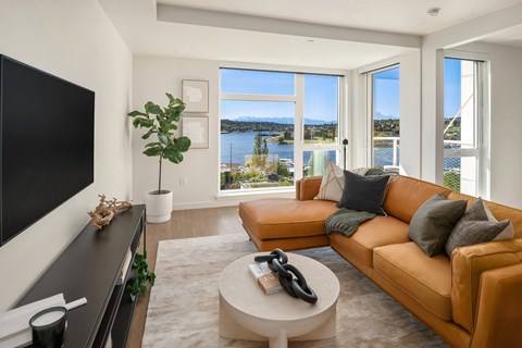 a living room with a leather couch and a television and a view of the water