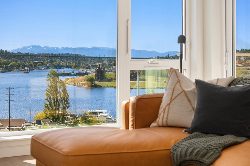a living room with a couch and a window overlooking a lake and mountains