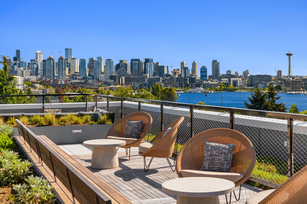 a rooftop deck with chairs and tables with a view of the city