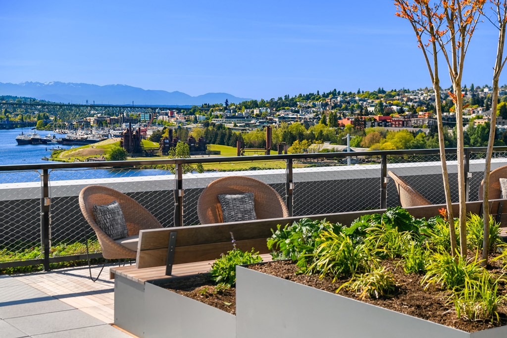 a balcony with chairs and a bench overlooking a river and a city