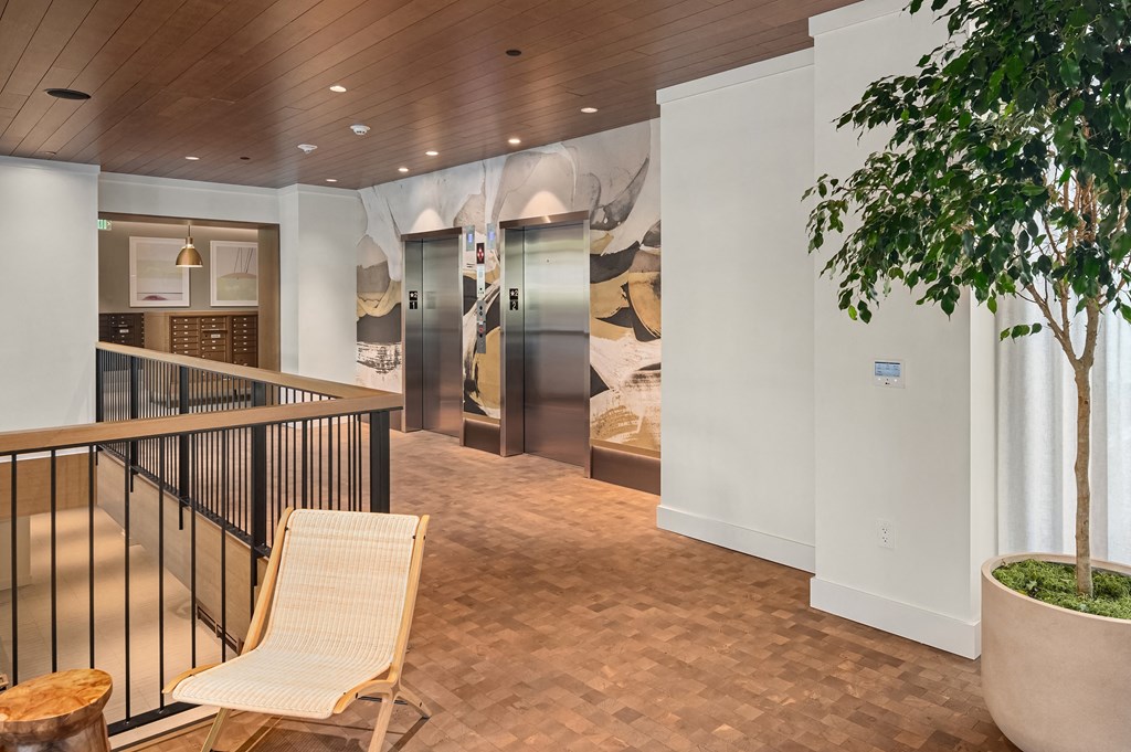 the lobby of a hotel with a chair and a tree