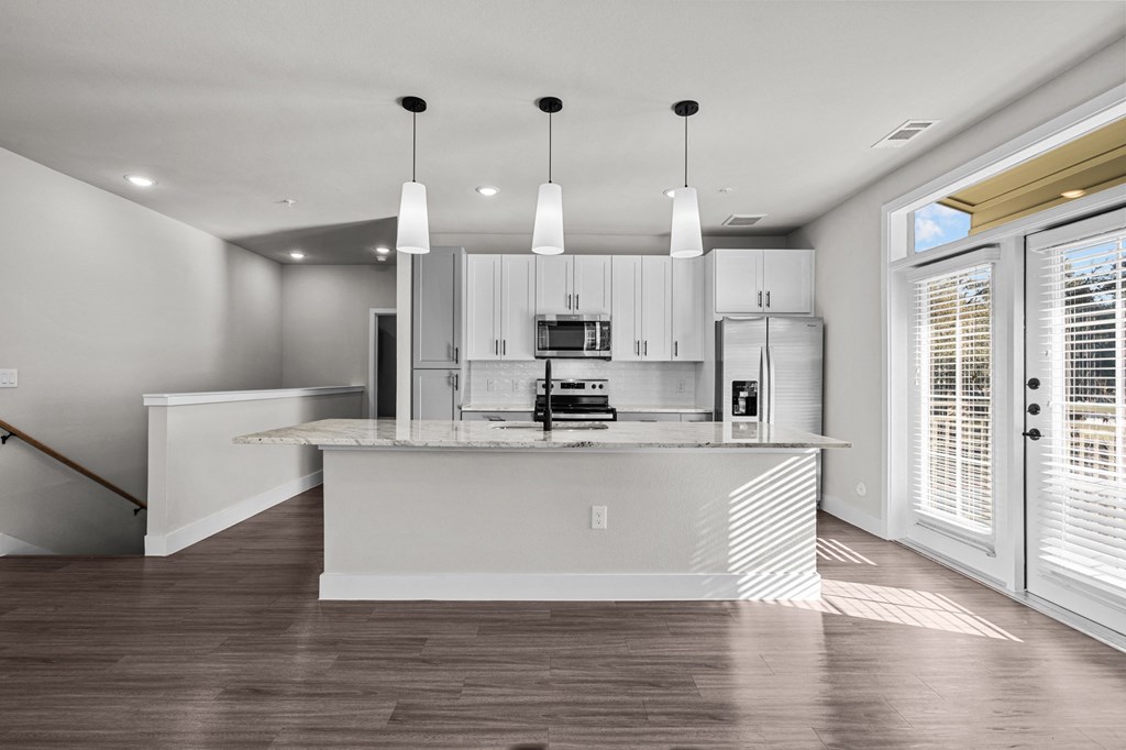 a kitchen with white cabinets and a large island with a marble counter top