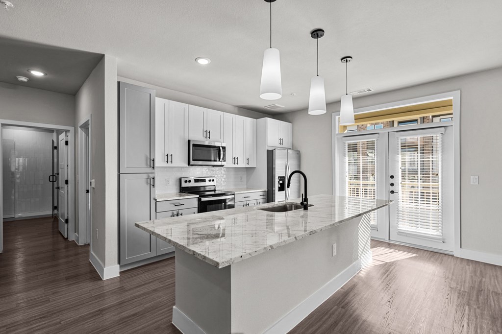 a kitchen with white cabinets and a marble counter top