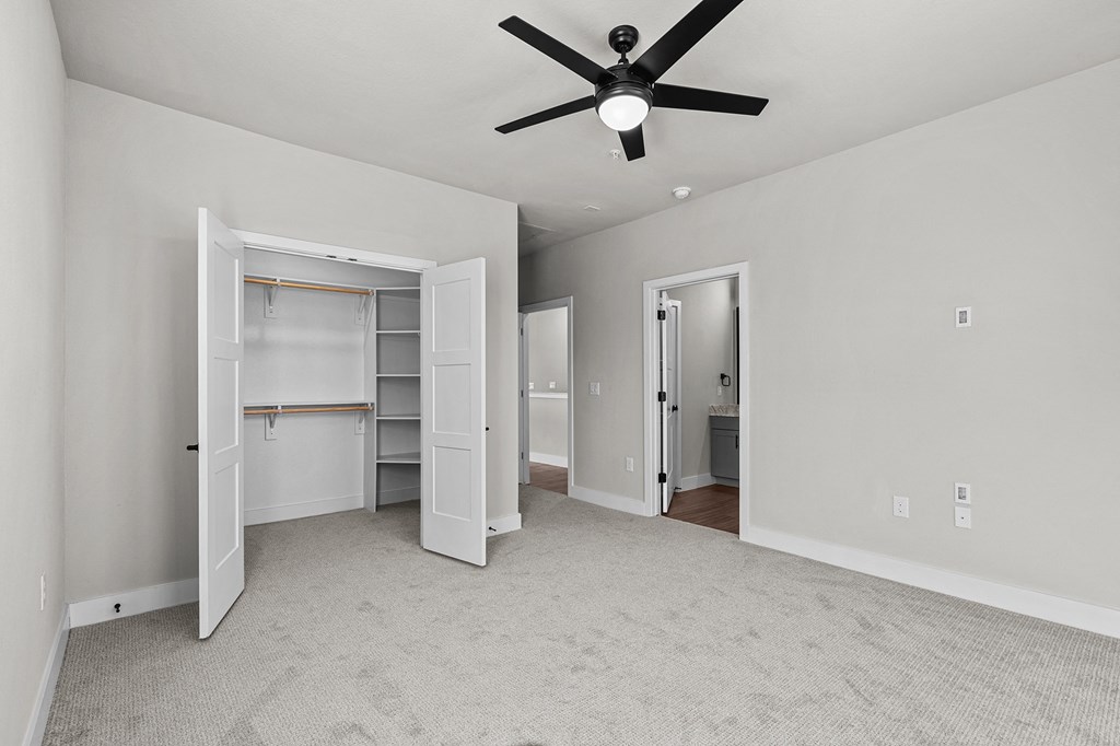 an empty bedroom with a ceiling fan and a closet