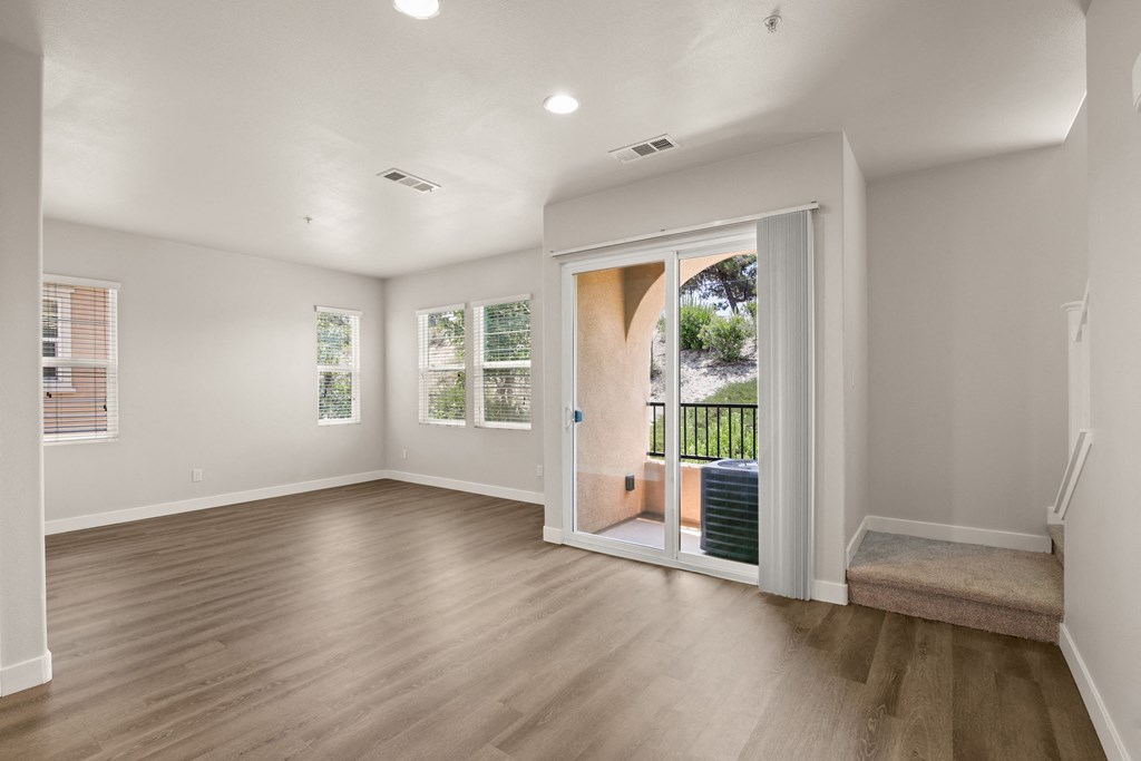 an empty living room with a sliding glass door to a patio