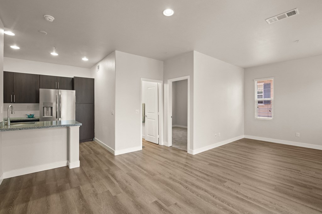 an empty living room and kitchen with a refrigerator and a sink