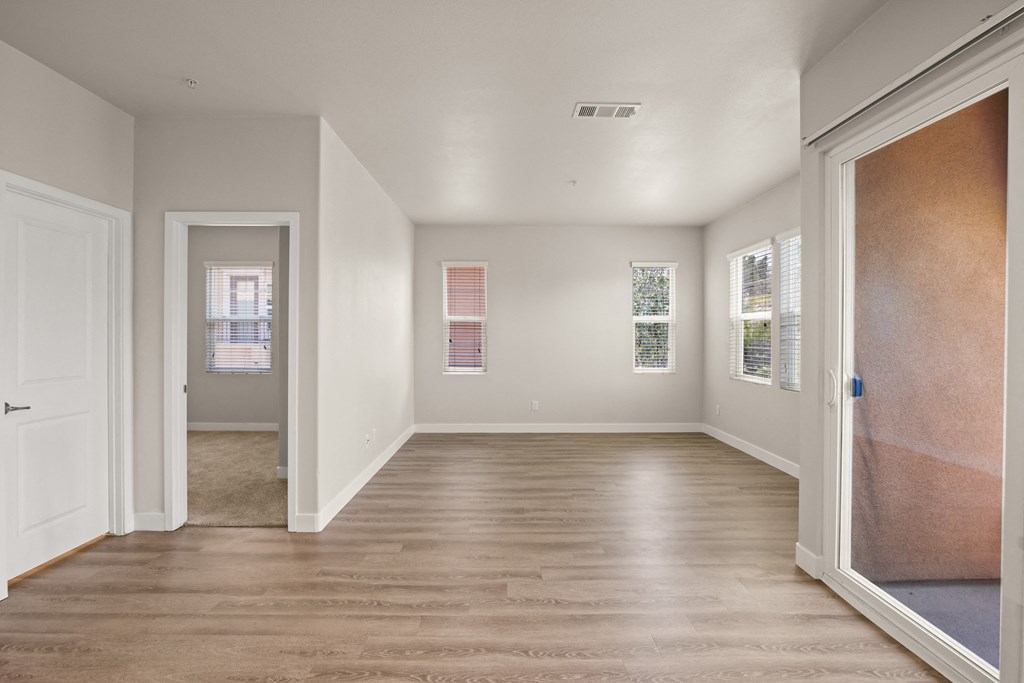 an empty living room with wood floors and white walls