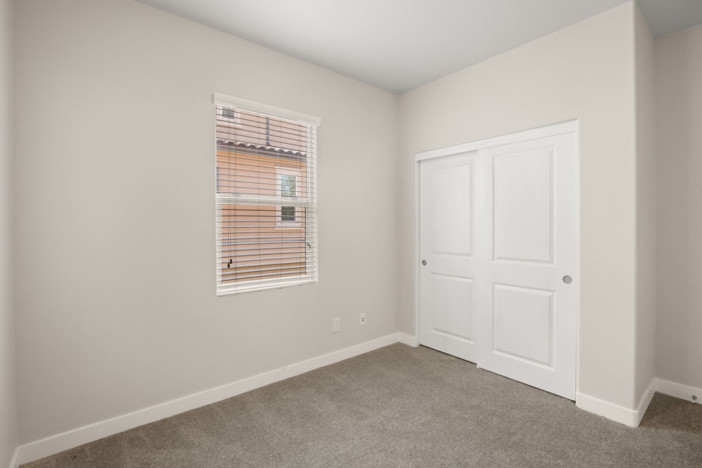 an empty bedroom with a door and a window