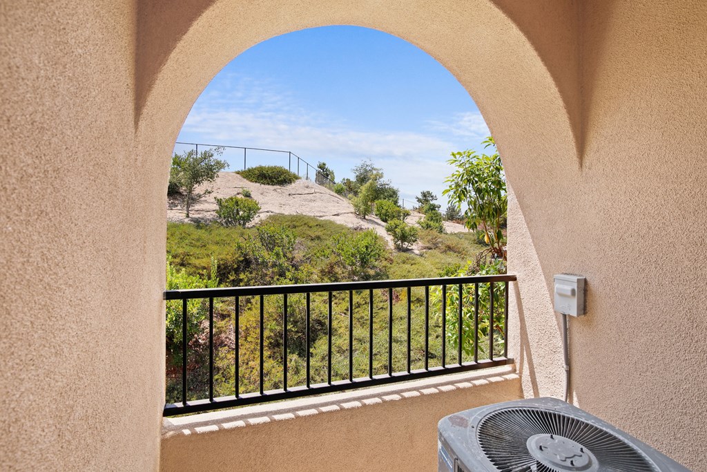 a balcony with a heater and a view of a garden