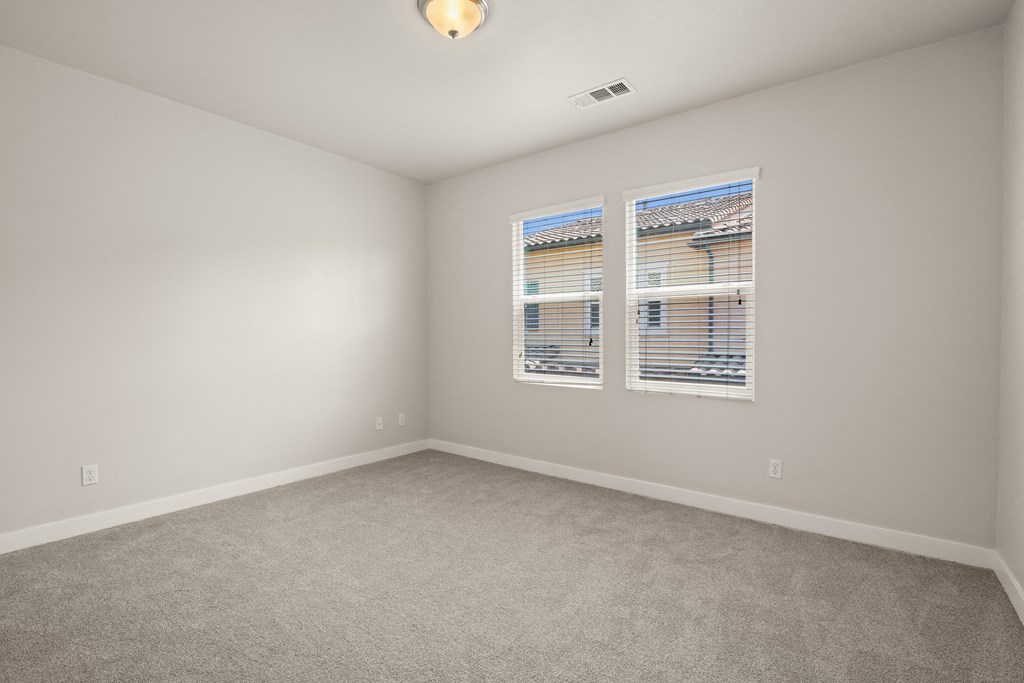 an empty room with two windows and a carpeted floor