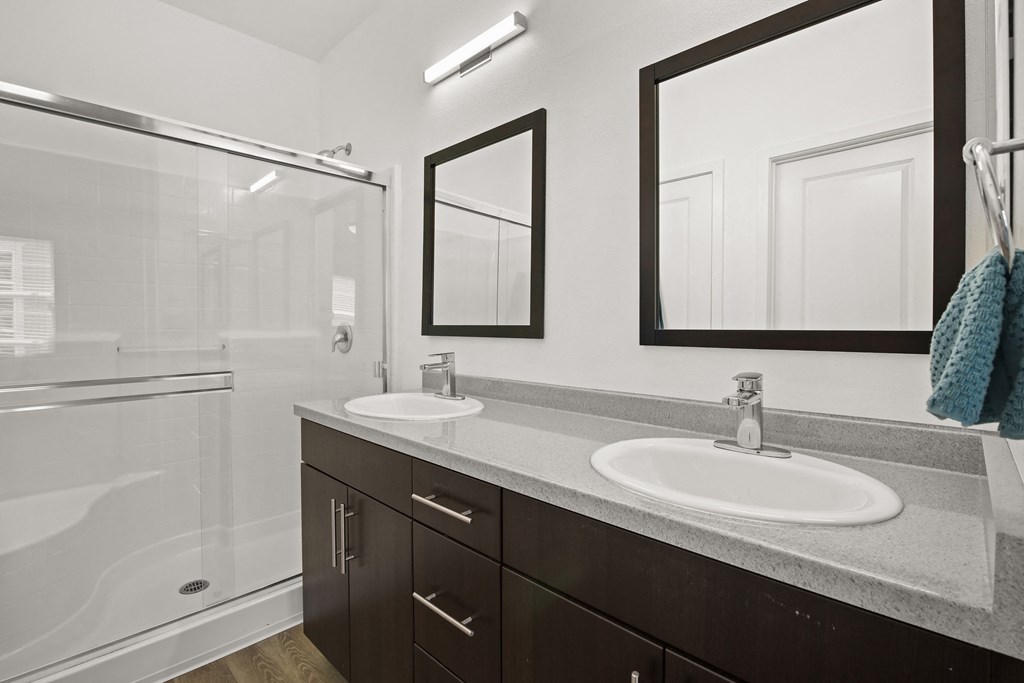 a bathroom with two sinks and a shower and two mirrors