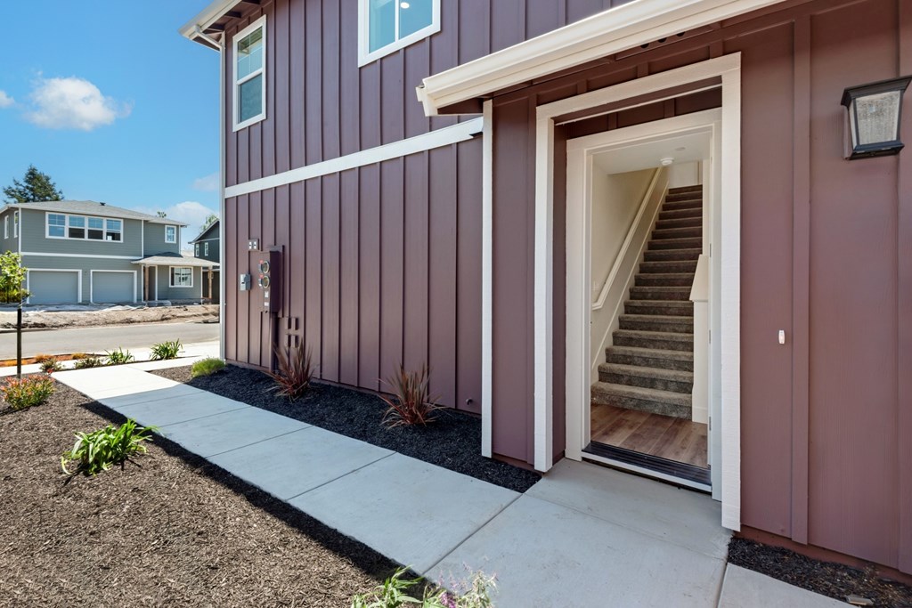 the front entrance of a home with stairs and a sidewalk