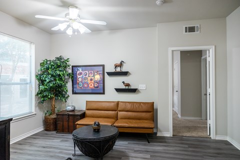 A living room with a brown couch and a ceiling fan.