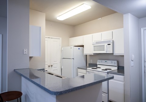 A kitchen with white appliances and a granite countertop.