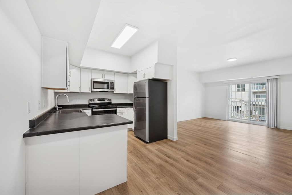 A kitchen with white cabinets and a black countertop.