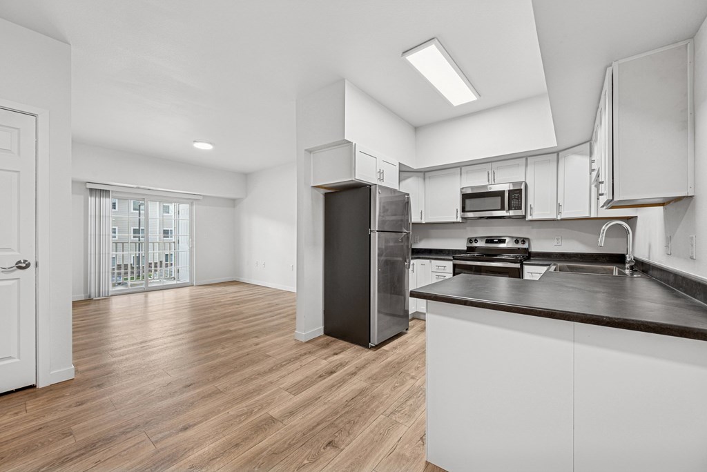 A kitchen with white cabinets and a black refrigerator.