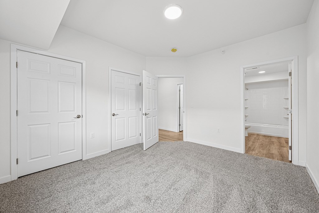 A room with white walls and a grey carpet.